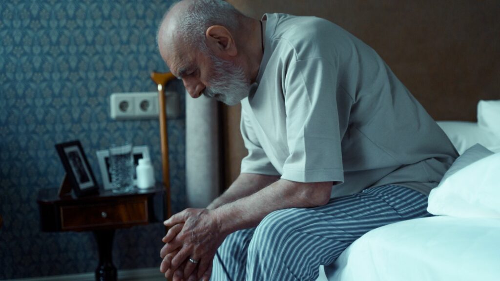 Weak elderly man in bed sitting